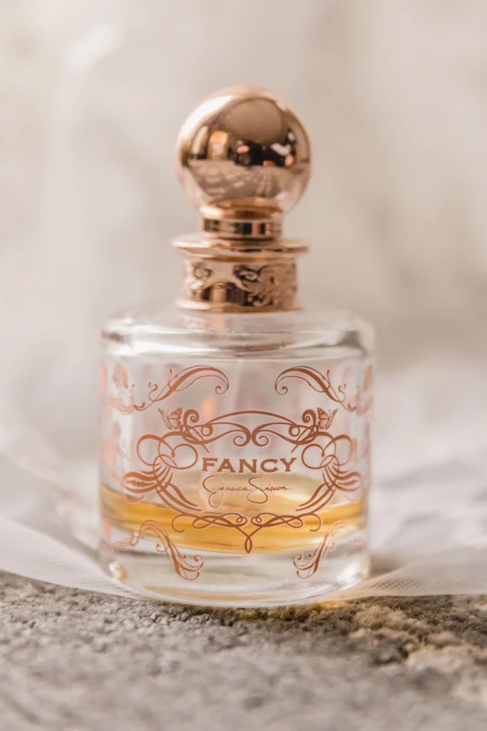 Boston Public Library Engagement Photos Session | Kelsey Sheehan Photography Rhode Island Wedding Photographer | Elegant perfume bottle labeled “Fancy” with ornate rose-gold designs and cap, resting on soft fabric, conveying luxury and sophistication.