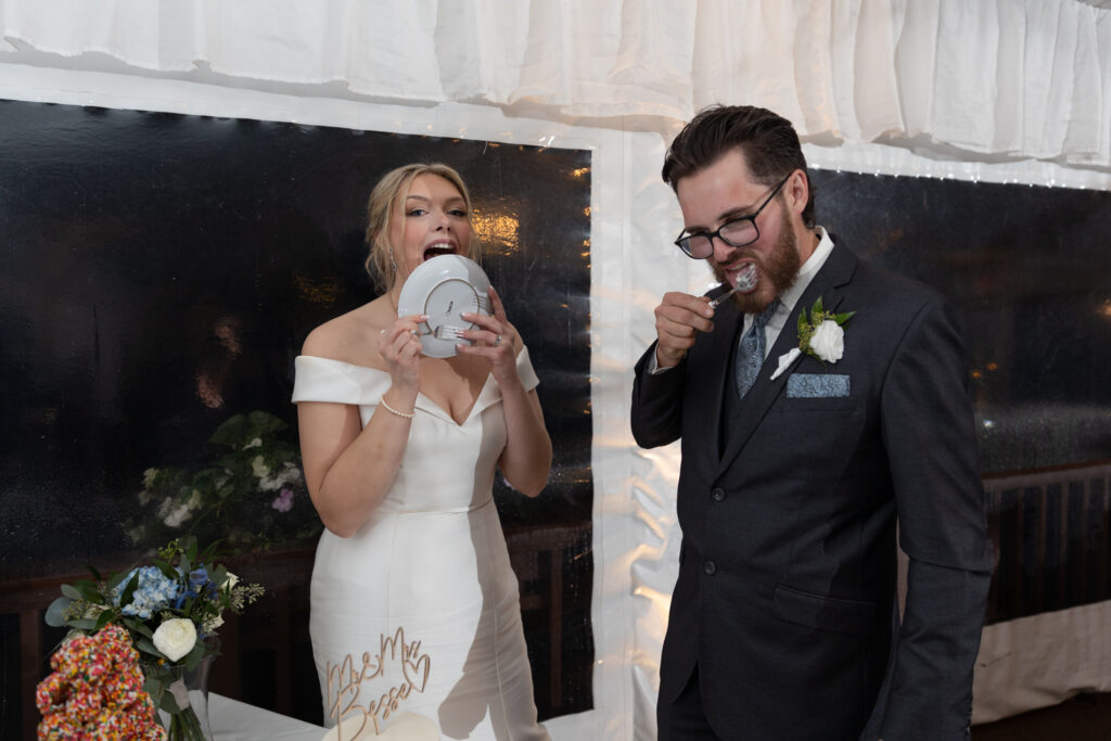 Couple being present during their wedding and licking the cake plate. Natural wedding photos at Chamberlain Farm