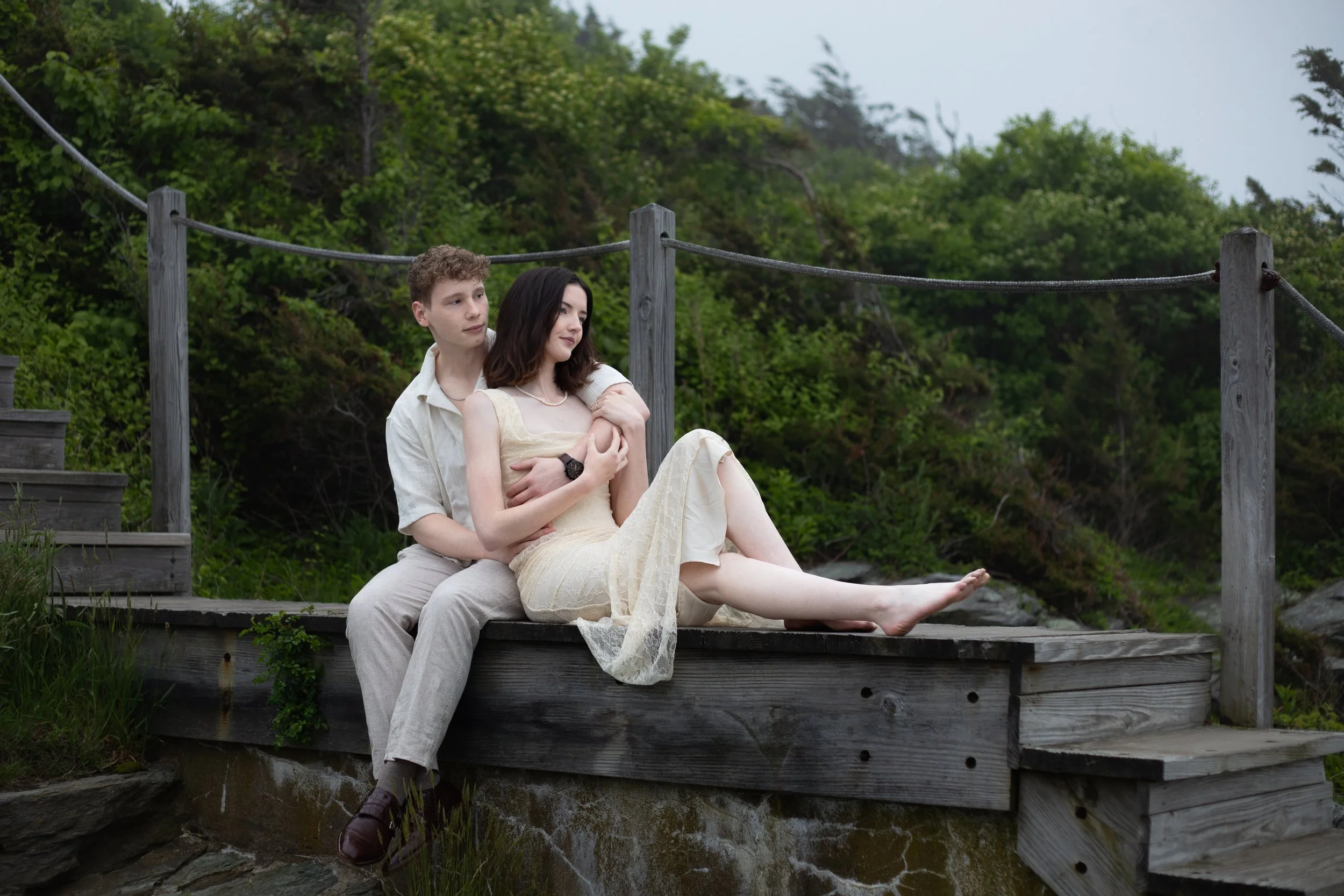 Newly engaged couple cuddling on the wooden stairs at Castle Hill Inn in Newport, Rhode Island.
