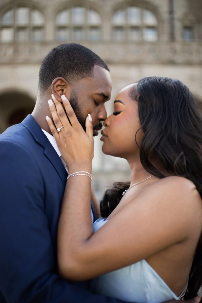 Ochre Court Newport | Kelsey Sheehan Photography Rhode Island Wedding Photographer | A couple embraces intimately, foreheads touching, in front of a historic building. She wears a ring and a strapless dress, exuding love and tenderness.