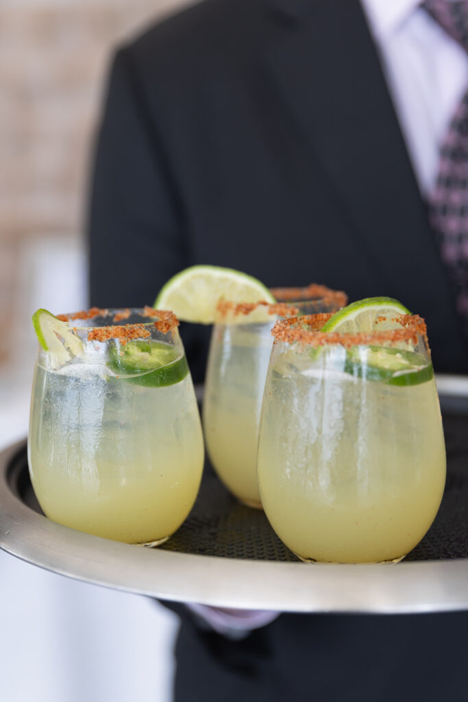 Wychmere Beach Club | Kelsey Sheehan Photography Rhode Island Wedding Photographer | Three margarita glasses with lime slices and chili-salted rims are on a tray held by a person in a suit, creating a sophisticated and refreshing vibe.
